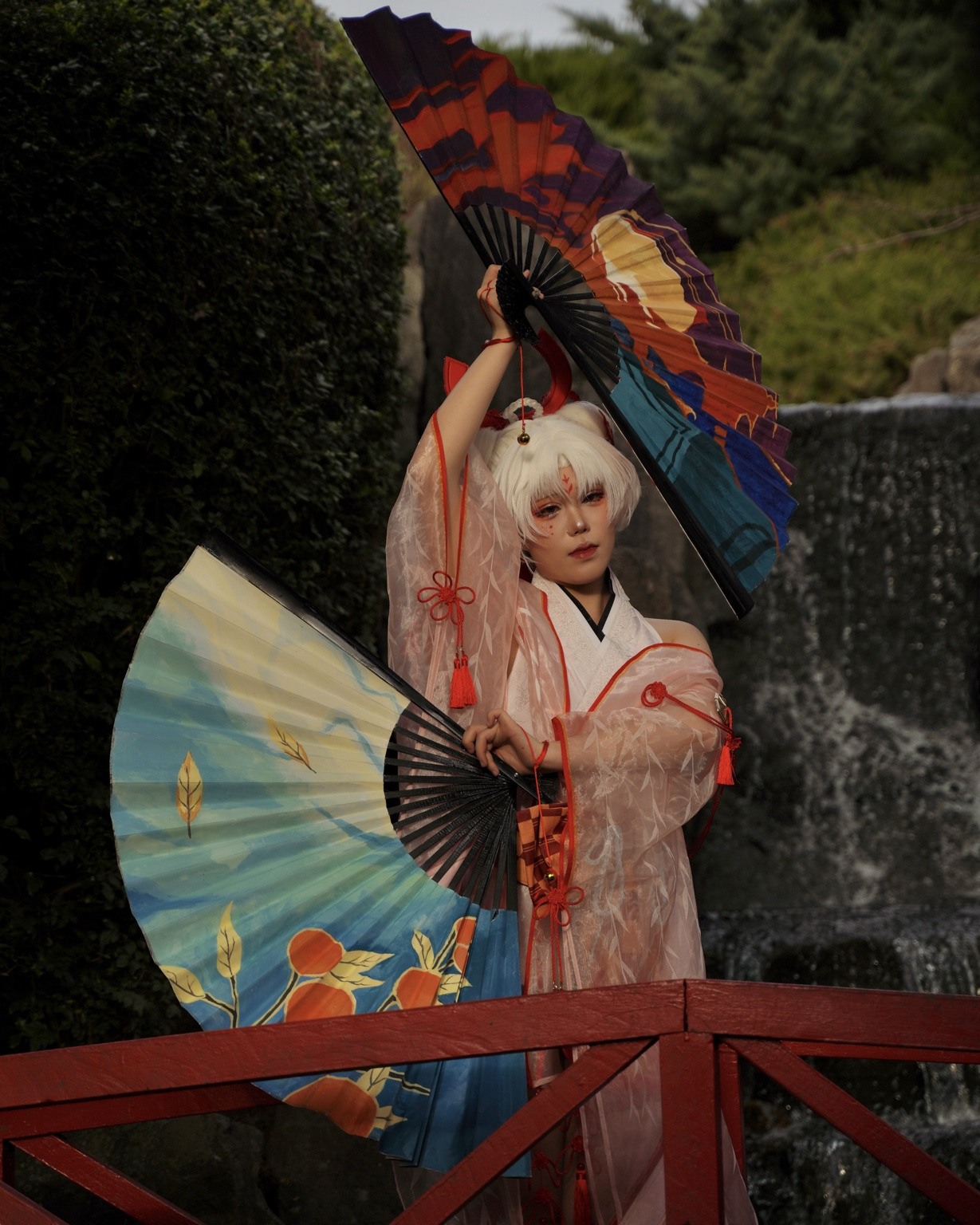Creative editorial portrait on a red bridge with two painted fans