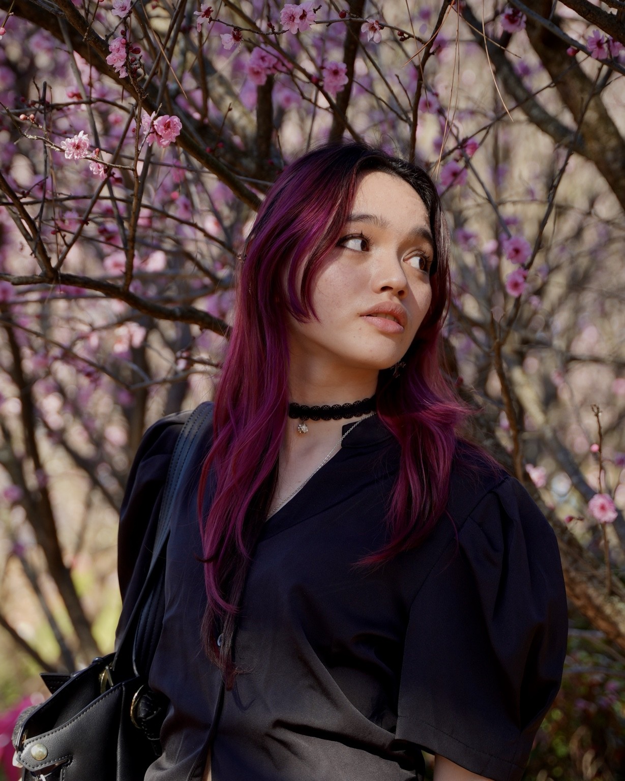 Close natural-light portrait framed by pink blossoms