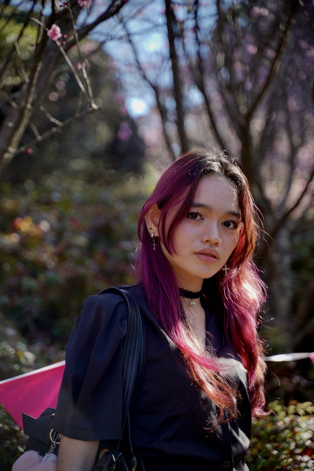 Close portrait with backlit magenta hair and garden bokeh