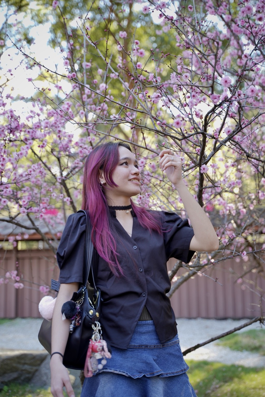 Smiling portrait reaching toward pink blossoms